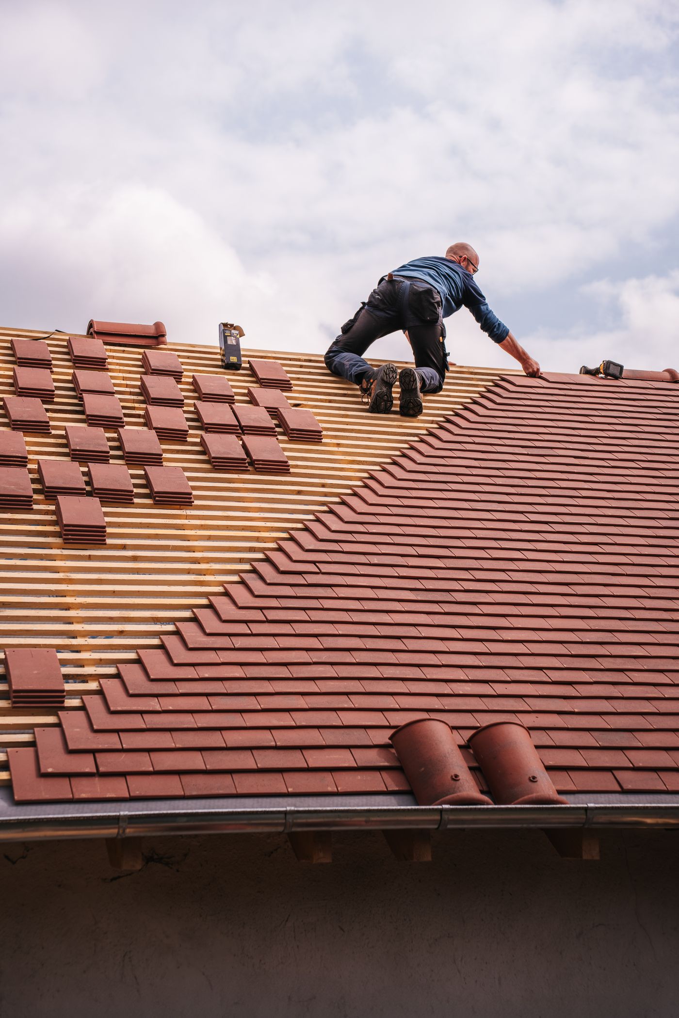 Tradesperson installing tiles on a residential roof